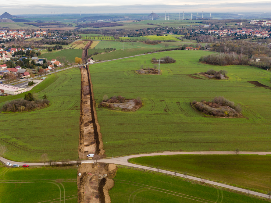 Abbildung 2: Blick über die Trasse von West nach Ost. Im Vordergrund die Anhöhe, im weiteren Verlauf der abfallende Hang Richtung Bendorf (Bildmitte links). Beidseitig und im Hintergrund sind verschiedene ehemalige Halden des Kupferschieferabbaus zu erkennen © Landesamt für Denkmalpflege und Archäologie Sachsen-Anhalt, Klaus Bentele.