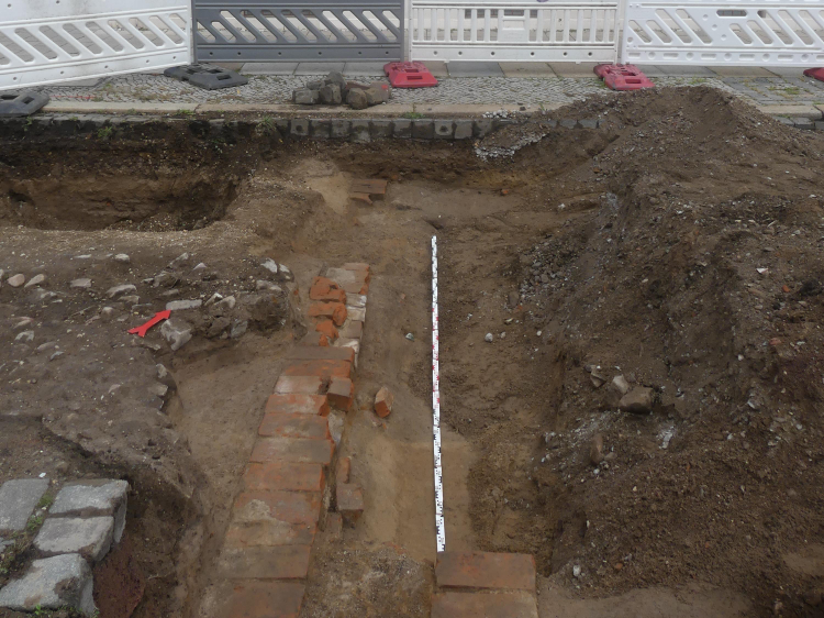 Abbildung 4: Aus Ziegelsteinen bestehende Fundamentreste der Akzisemauer. Im Hintergrund der Westflügel der einstigen Leopoldkaserne, die von 1852 bis 1855 erbaut wurde. Heute befindet sich in dem Gebäude das Ordnungsamt der Stadt Dessau-Roßlau. Blick nach Norden. © Landesamt für Denkmalpflege und Archäologie Sachsen-Anhalt, Helge Jarecki.