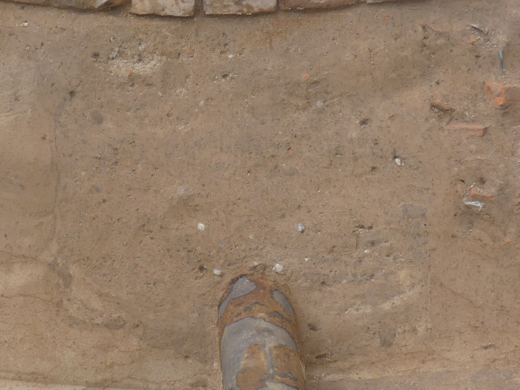 Abbildung 7: Das Rohr liegt auf der Sohle eines Erdtunnels, dessen oberer Abschluss knapp unter der Mauer endet. Die geringe Festigkeit des Füllmaterials führte zu einem leichten Einsinken der in situ befindlichen Ziegelsteinreihe (Leitung 2). Blick nach Westen. © Landesamt für Denkmalpflege und Archäologie Sachsen-Anhalt, Helge Jarecki.