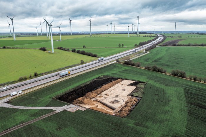 Abbildung 2: Drohnenaufnahme von Schnitt 6 der Fundstelle 15, Nauendorf, Saalekreis. Endsprechend des Verlaufs der Stromtrasse liegt die Fundstelle unweit der Bundesautobahn 14 in einer flachen Landschaft zwischen dem Saaletal und der Fuhneaue, am Fuße des markanten Petersberg. © Landesamt für Denkmalpflege und Archäologie Sachsen-Anhalt, Klaus Bentele.