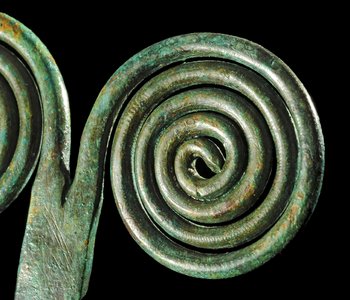 Abbildung 4: Das Detail der Brillennadel zeigt die geritzten Verzierungen auf den Spiralen und Schleifspuren auf dem verbreiterten Schaft. © Landesamt für Denkmalpflege und Archäologie Sachsen-Anhalt, Andrea Hörentrup.